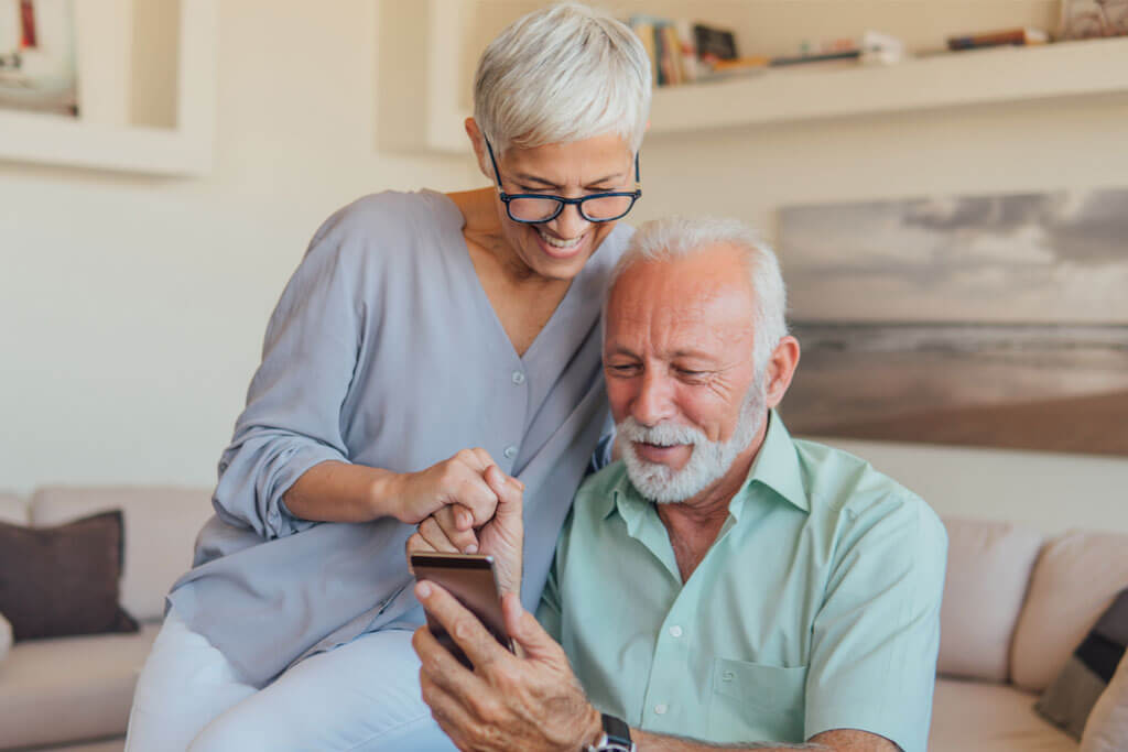 Online Hearing Canada older couple using smartphone app on bluetooth phone.